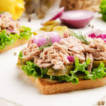 Tuna sandwiches with pickled cucumbers and onions on parchment paper
